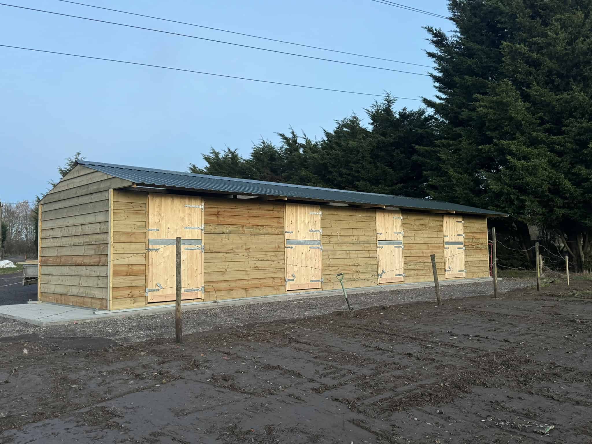 New wooden stable building built by Sussex Stables for horse boarding and equestrian activities. Featuring galvanised steel skids and steel roofing